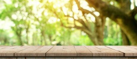 table en bois vide et bokeh défocalisé et arrière-plan flou des arbres de jardin avec la lumière du soleil. modèle d'affichage du produit. photo