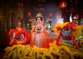 chinois femme avec Jaune et rouge les Lions il est pris en considération à améliorer le la prospérité pour soi-même sur le occasion de le chinois Nouveau année Festival chaque année photo