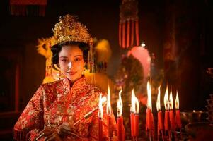 chinois femme faire vœux, prier, et lumière bougies. sur le occasion de le annuel chinois Nouveau année festival, dans une vénéré tombeau ou temple photo