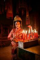 chinois femme faire vœux, prier, et lumière bougies. sur le occasion de le annuel chinois Nouveau année festival, dans une vénéré tombeau ou temple photo