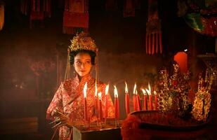 chinois femme faire vœux, prier, et lumière bougies. sur le occasion de le annuel chinois Nouveau année festival, dans une vénéré tombeau ou temple photo