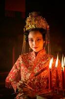 chinois femme faire vœux, prier, et lumière bougies. sur le occasion de le annuel chinois Nouveau année festival, dans une vénéré tombeau ou temple photo