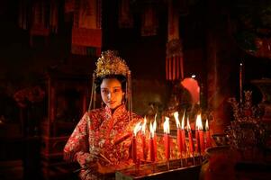 chinois femme faire vœux, prier, et lumière bougies. sur le occasion de le annuel chinois Nouveau année festival, dans une vénéré tombeau ou temple photo