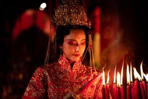 chinois femme faire vœux, prier, et lumière bougies. sur le occasion de le annuel chinois Nouveau année festival, dans une vénéré tombeau ou temple photo