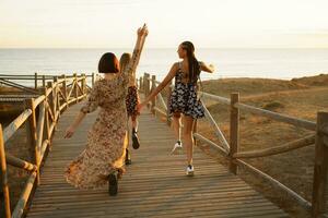 détendu diverse femmes joyeusement fonctionnement sur promenade sur rivage photo