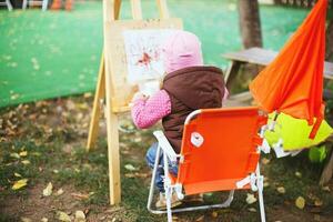 peu fille dessine sur le chevalet. le enfant des peintures photo