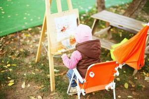 peu fille dessine sur le chevalet. le enfant des peintures photo