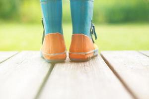 caoutchouc bottes sur une en bois Contexte. enfants caoutchouc bottes sur une Contexte de vert herbe photo