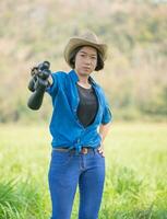 femme porter un chapeau et tenir des jumelles dans un champ d'herbe photo