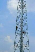 peindre des antennes de téléphones portables et Internet pour rehausser la beauté par de jeunes travailleurs au corps dur avec l'audace d'atteindre des sommets est un travail dangereux. photo