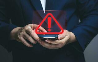 homme d'affaires utilisant un smartphone avec un triangle d'avertissement indiquant une erreur système. concepts de maintenance du système, de sécurité, d'antivirus et d'accès anti-piratage aux données critiques. photo