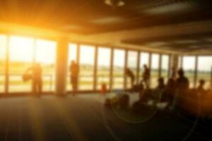 flou image de gens et touristique attendre pour le air avion dans le aéroport Terminal hall avec Soleil et lentille éclater Contexte. photo