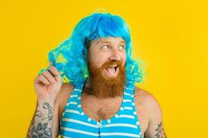 étonné homme avec la vie bouée, maillot de bain et bleu perruque actes comme une étonné femme photo