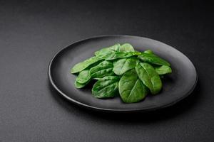 Frais vert épinard feuilles sur une noir céramique assiette photo