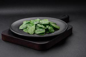 Frais vert épinard feuilles sur une noir céramique assiette photo