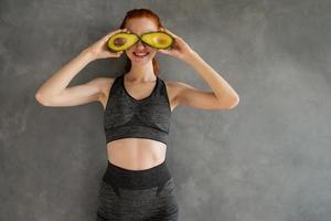 athlétique fille avec Gym vêtements mange Avocat à maison. photo