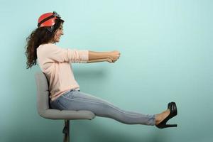 femme avec rouge casque pense à conduire une vite auto. cyan Contexte. photo