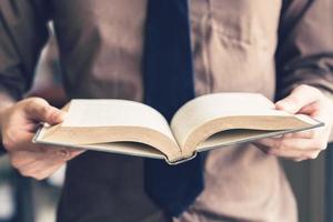 affaires homme main en portant livre et en train de lire à la fenêtre. photo