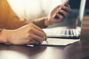 affaires homme main l'écriture et en portant téléphone dans bureau. photo