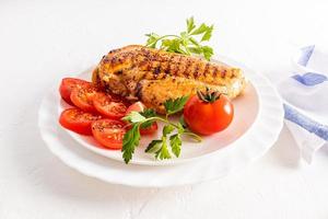 de face vue de une assiette avec juteux grillé poulet filet et tomate tranches. délicieux en bonne santé nourriture sans pour autant cuisine dans huile. régime. photo