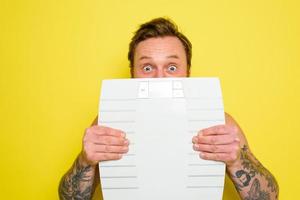 étonné homme avec barbe et tatouages est caché derrière le Balance photo