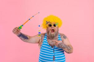 graisse étonné homme avec barbe et des lunettes de soleil avoir amusement avec le pêche pôle photo