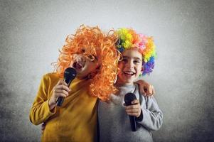 deux enfant chanter une chanson avec microphone et marrant perruque photo