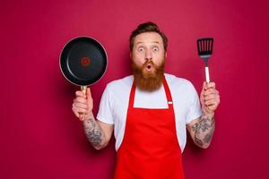 demandé chef avec barbe et rouge tablier est prêt à cuisinier photo