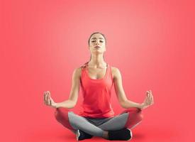 Jeune fille relaxant dans yoga position sur rouge Contexte photo