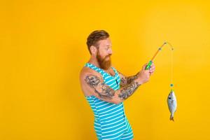 homme avec barbe et maillot de bain pris une poisson photo