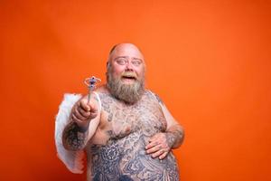 graisse content homme avec barbe , tatouages et ailes actes comme un la magie Fée photo