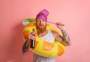 étonné homme est prêt à nager avec une Donut bouée de sauvetage avec Bière et cigarette dans main photo