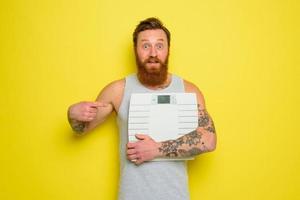 étonné homme avec barbe et tatouages détient un électronique équilibre photo