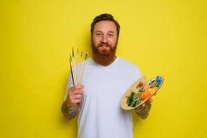 content homme avec barbe et tatouage est prêt à dessiner avec brosses photo