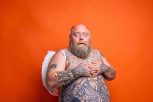 graisse étonné homme avec barbe , tatouages et ailes actes comme un ange photo