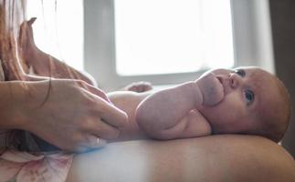 mère avec une bébé sur une lit par le fenêtre photo