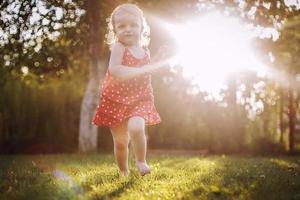 content bébé souriant. peu fille fonctionnement à le coucher du soleil photo