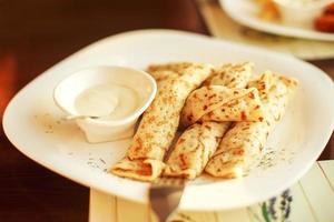 Crêpes roulé dans une paille sur une assiette avec acide crème photo