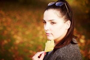 portrait de une fille avec un l'automne feuille dans sa main photo