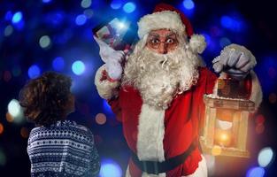 Père Noël claus est donnant une présent pour Noël à une peu garçon photo