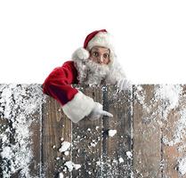 Père Noël claus indiquer quelque chose avec main dans une en bois mur photo