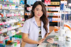 pharmacienne asiatique utilise une tablette numérique dans la pharmacie