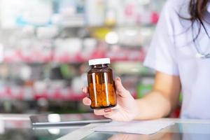 le pharmacien tient une bouteille de médicament dans la pharmacie photo