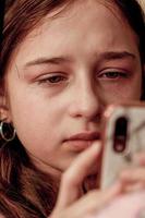 une adolescent fille est pleurs à la recherche à une téléphone intelligent. une adolescent fille est bouleversé. photo