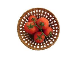 Tomates dans un panier en osier sur fond blanc photo