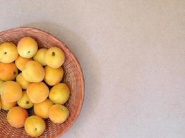 abricots dans un panier en osier sur fond beige photo