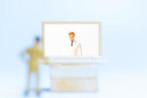 Personnes miniatures d'un patient de sexe masculin en consultation avec un médecin à l'aide d'un appel vidéo sur un ordinateur portable, concept de médecin en ligne photo