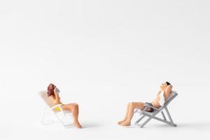 Gens miniatures en train de bronzer sur des chaises longues sur fond blanc, concept de l'été photo