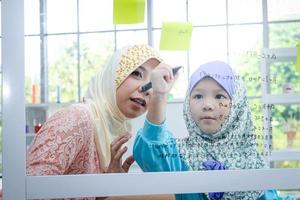 islamique femelle prof enseigné mathématiques à une peu fille dans le Salle de classe. le concept de enfants éducation photo