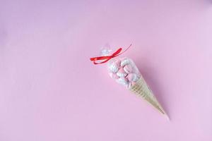 coloré brillant meringues dans gaufre biscuits dans transparent emballage mensonge sur une rose Contexte photo